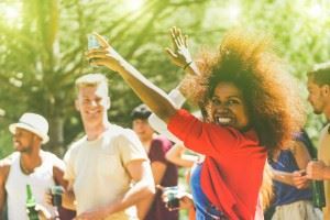 African American woman smiling with her hands raised high at a party/cookout with friends