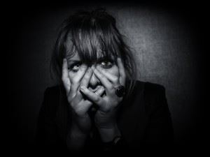 Woman in black and white covering her face with her hands