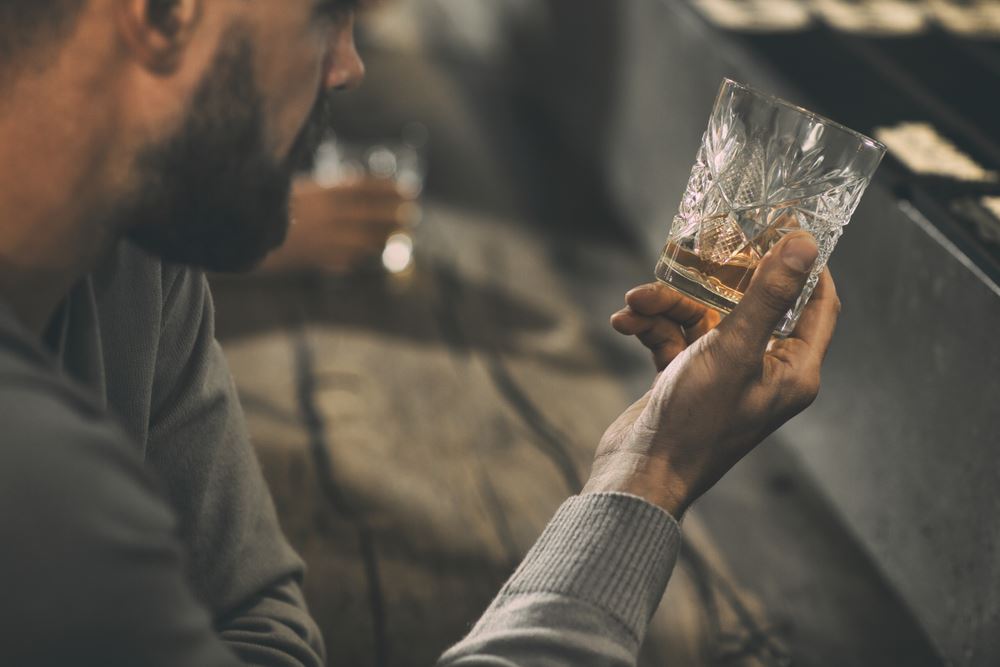 Man looking at his almost empty rocks glass filled with whiskey/bourbon