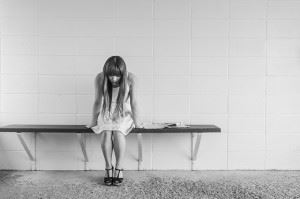 Skinny girl sitting on a bench in a waiting area leaned over anxiously