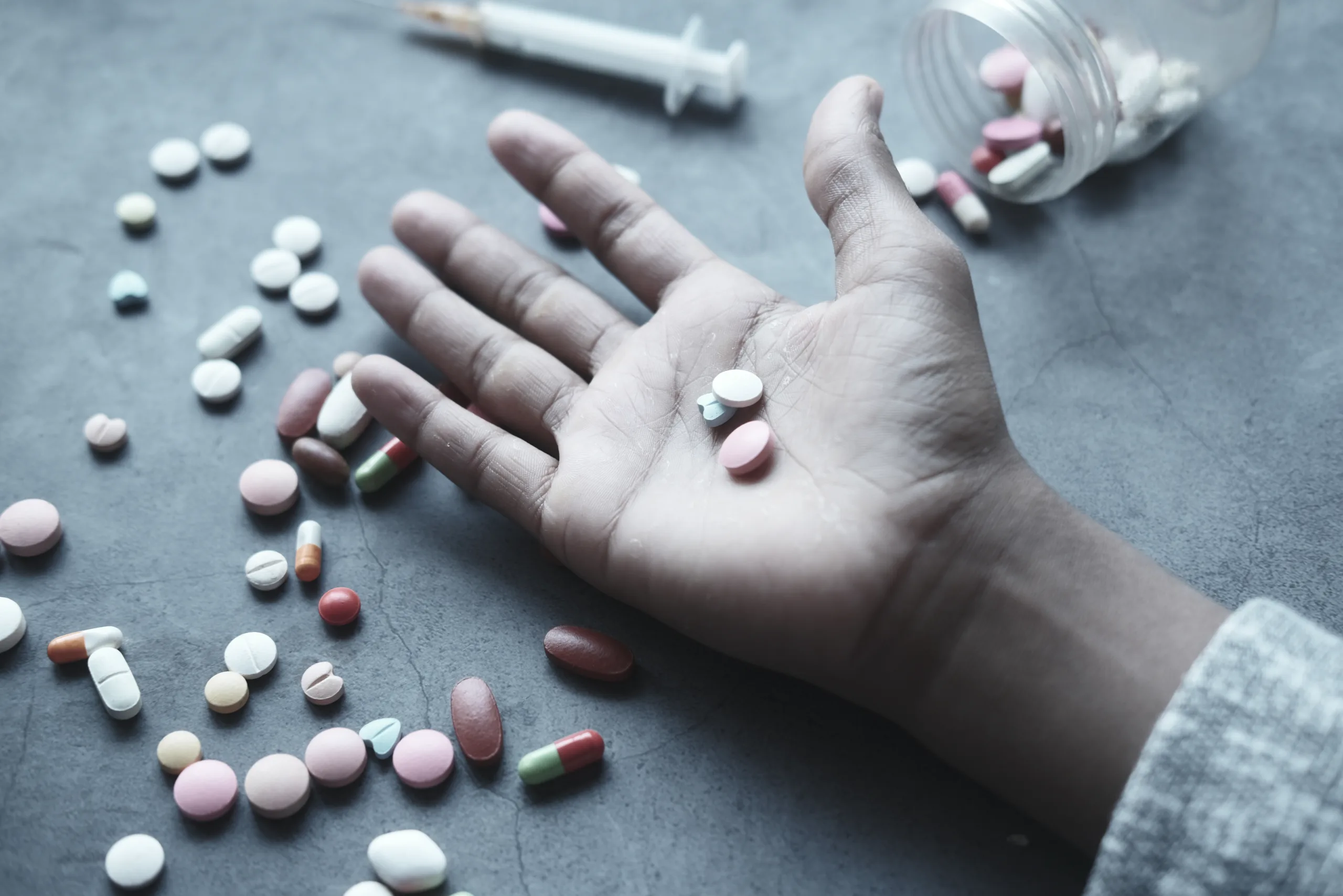 drug abuse concept with many pills on hand against black background .